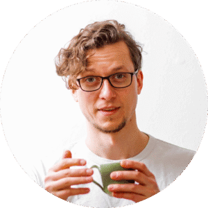 Mann mit Brille hält Tasse und lächelt, Fokus auf Männergesundheit.