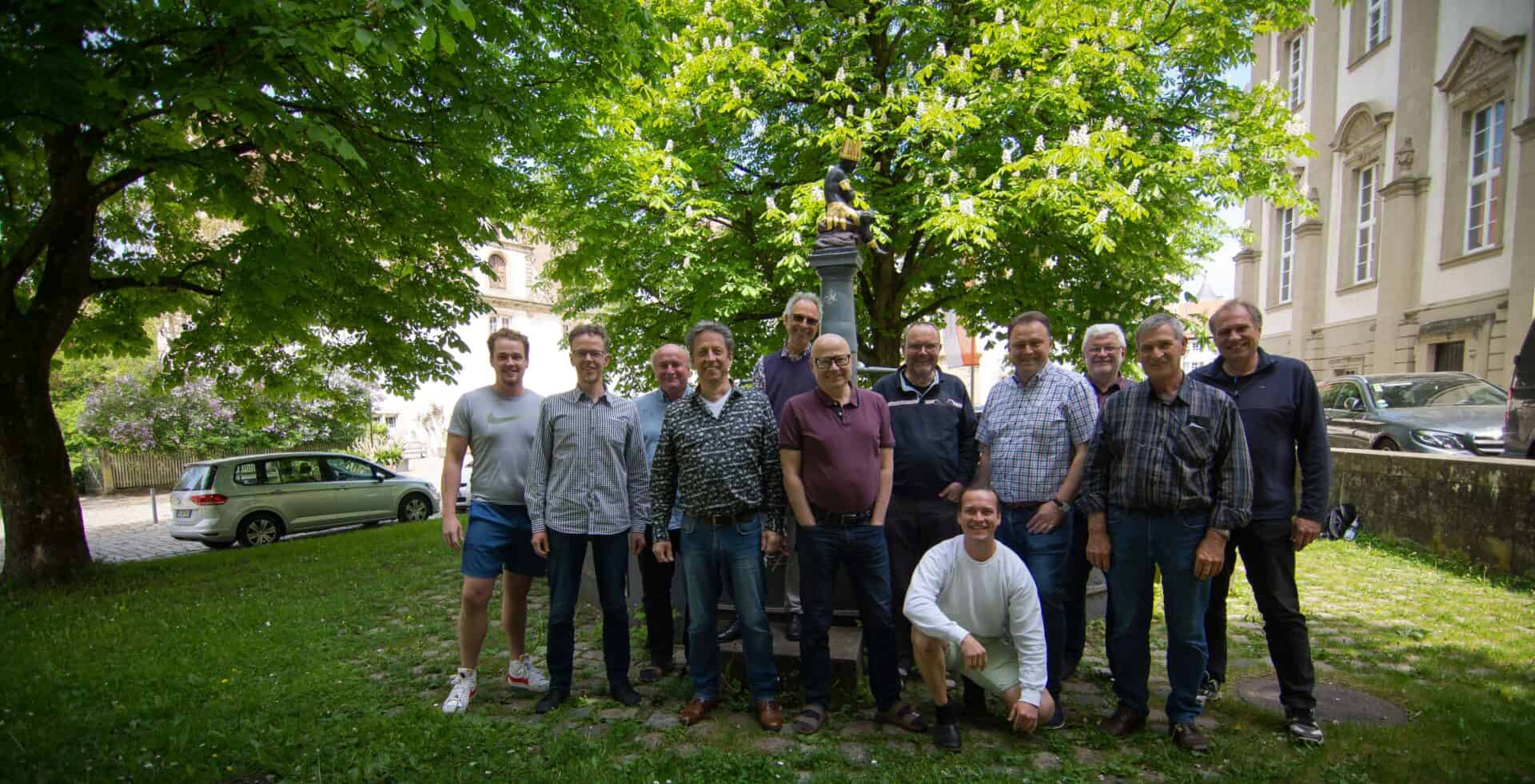 Gruppe von Männern im Park bei MALEvolution, umgeben von Bäumen und Natur.