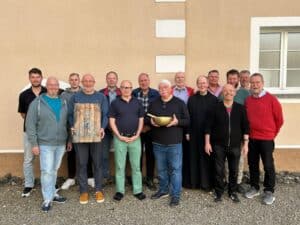 Gruppe von Männern bei MALEvolution Treffen, die zusammen vor einem Gebäude stehen.