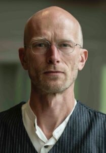 Mann mit Brille und ernstem Blick, männlich, professionell, Selbstbewusst.