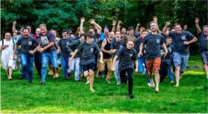 Jungs laufen lachend im Grünen bei einem Abenteuerwochenende.