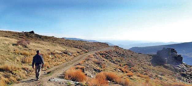 Mann wandert auf Bergpfad in der Natur bei Sonnenaufgang.